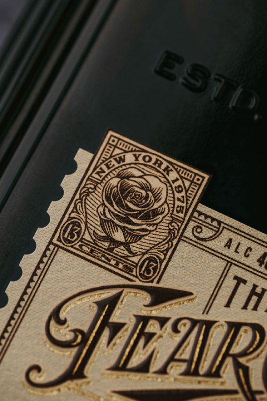 Макро‑кадр золотой этикетки «The Fear City» с орнаментом и розой, детализированная типографика, тиснение и винтажная графика в стиле ар‑деко.