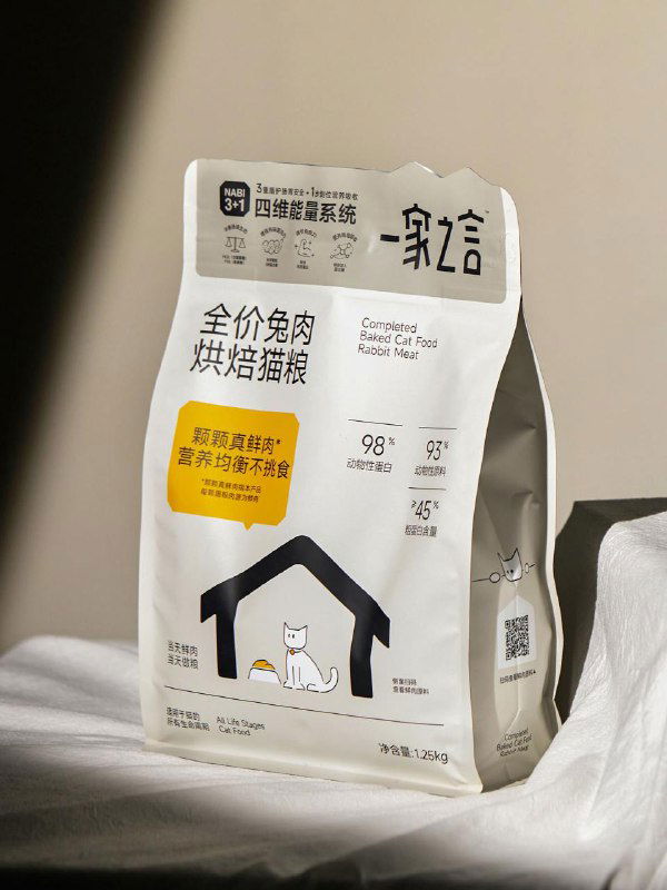 Упаковка корма на текстильной поверхности: крупный план с мягким светом, видна простая графика дома и кота, подчёркнуты детали печати