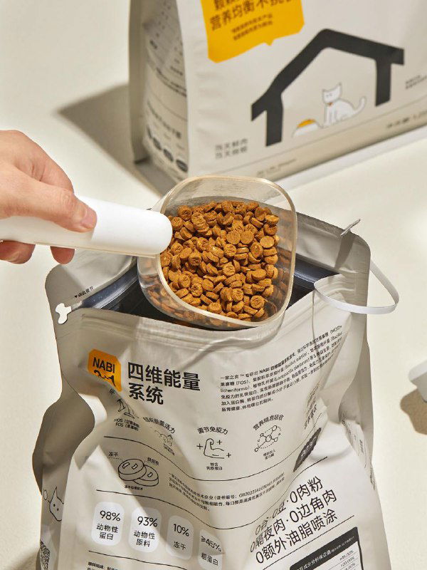 Крупный план мерной ложки с кормом над раскрытой упаковкой: показана текстура гранул и удобство дозирования продукта в повседневном использовании