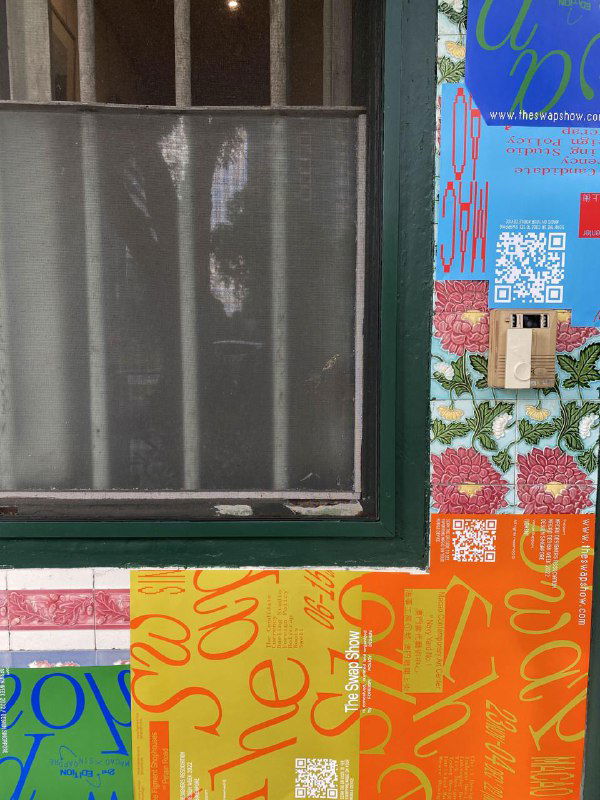 Крупный план двери и стены, покрытой рекламными наклейками и постерами The Swap Show, фрагмент уличной среды и визуальной кампании.