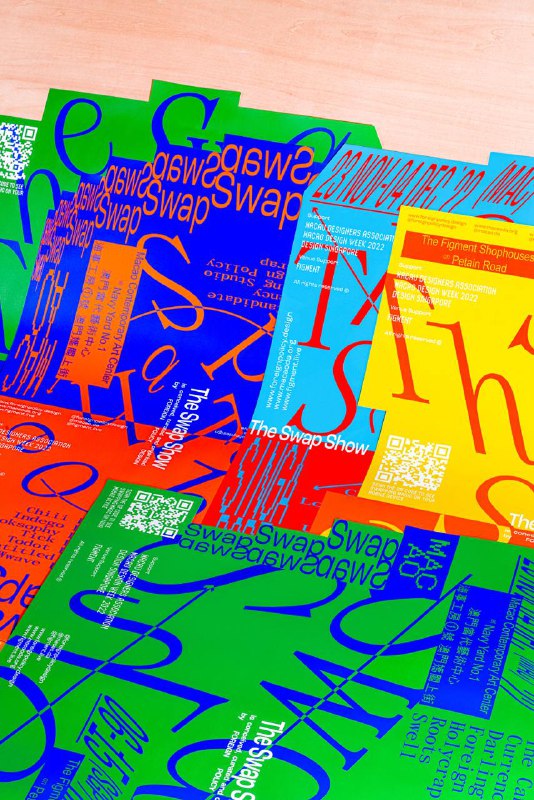 Стопка цветных постеров The Swap Show с крупной типографикой и QR-кодом на светлой поверхности, видна общая стилистика айдентики и материалы печати.