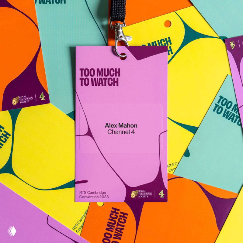 Бейджи и карточки участников с яркой абстрактной графикой и надписями «Too Much To Watch», крупный план на детали оформления конференции.