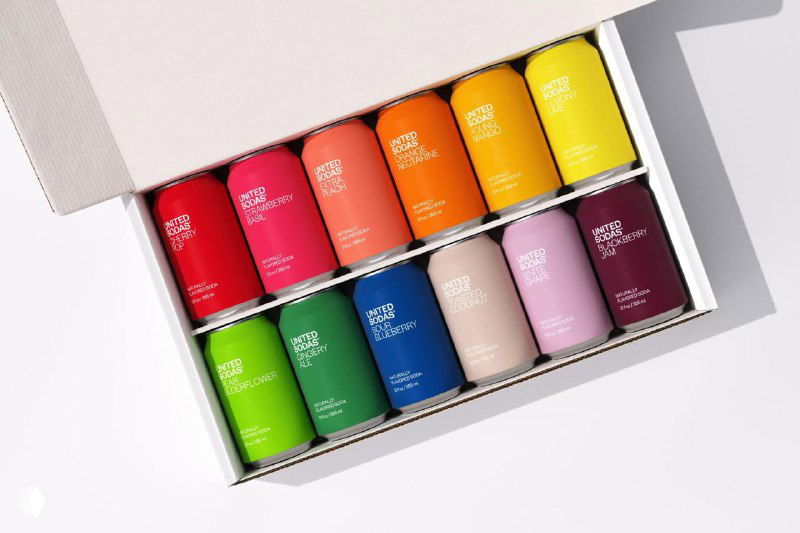 Набор банок United Sodas в подарочной коробке: ровные ряды разноцветных жестяных банок с минимальным текстом на этикетке и чистой упаковкой.
