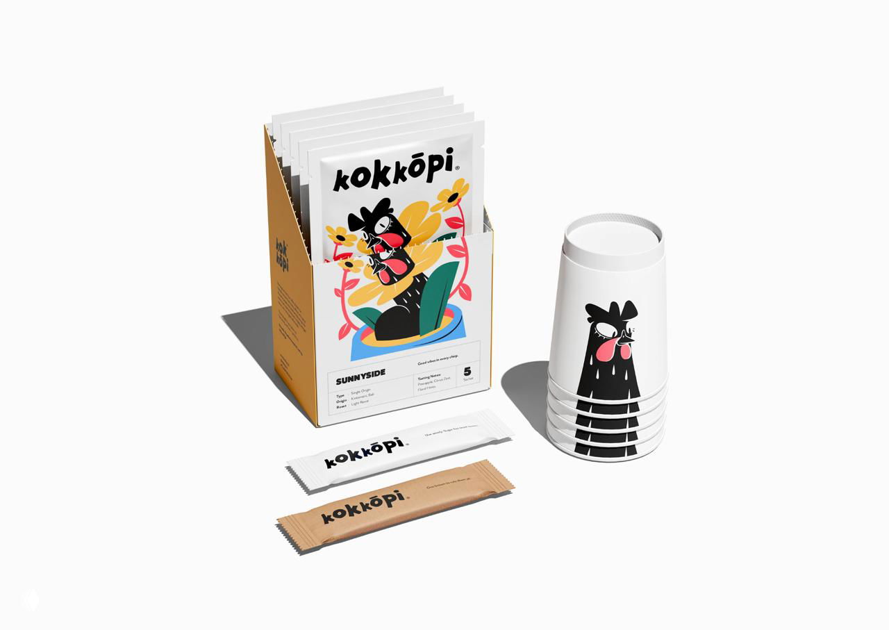 Диспенсер и бумажные стаканчики Kokkōpi: пачки стикеров, сахарные пакеты и стаканы с иллюстрацией петуха‑маскота в фирменном стиле.