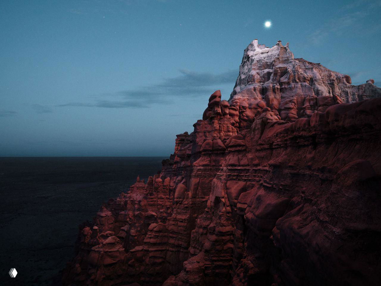 Одиночный каменный шпиль в свете дрона и над ним светящееся кольцо — след от пролёта источника света в длинной выдержке.