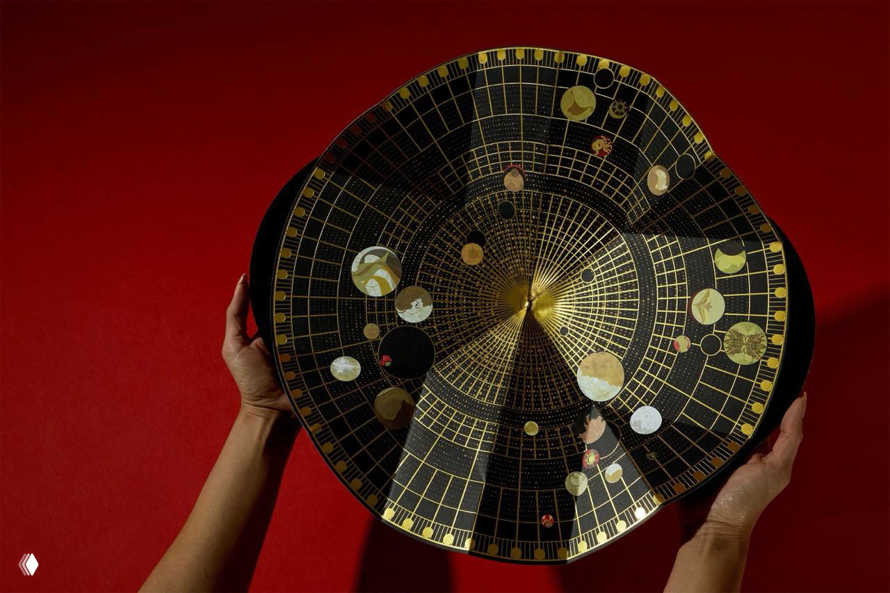 Внутренняя сторона крышки с тонкой золотой картой и сеткой: астро-орнамент, звёздные круги и маленькие иллюстрации на красном фоне, рука держит коробку.