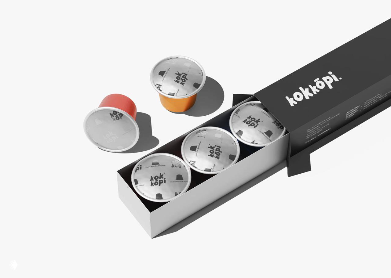 Коробка с капсулами Kokkōpi: чёрно‑белая коробка, открытый лоток с капсулами и фирменный логотип на крышках с чистой стилистикой.