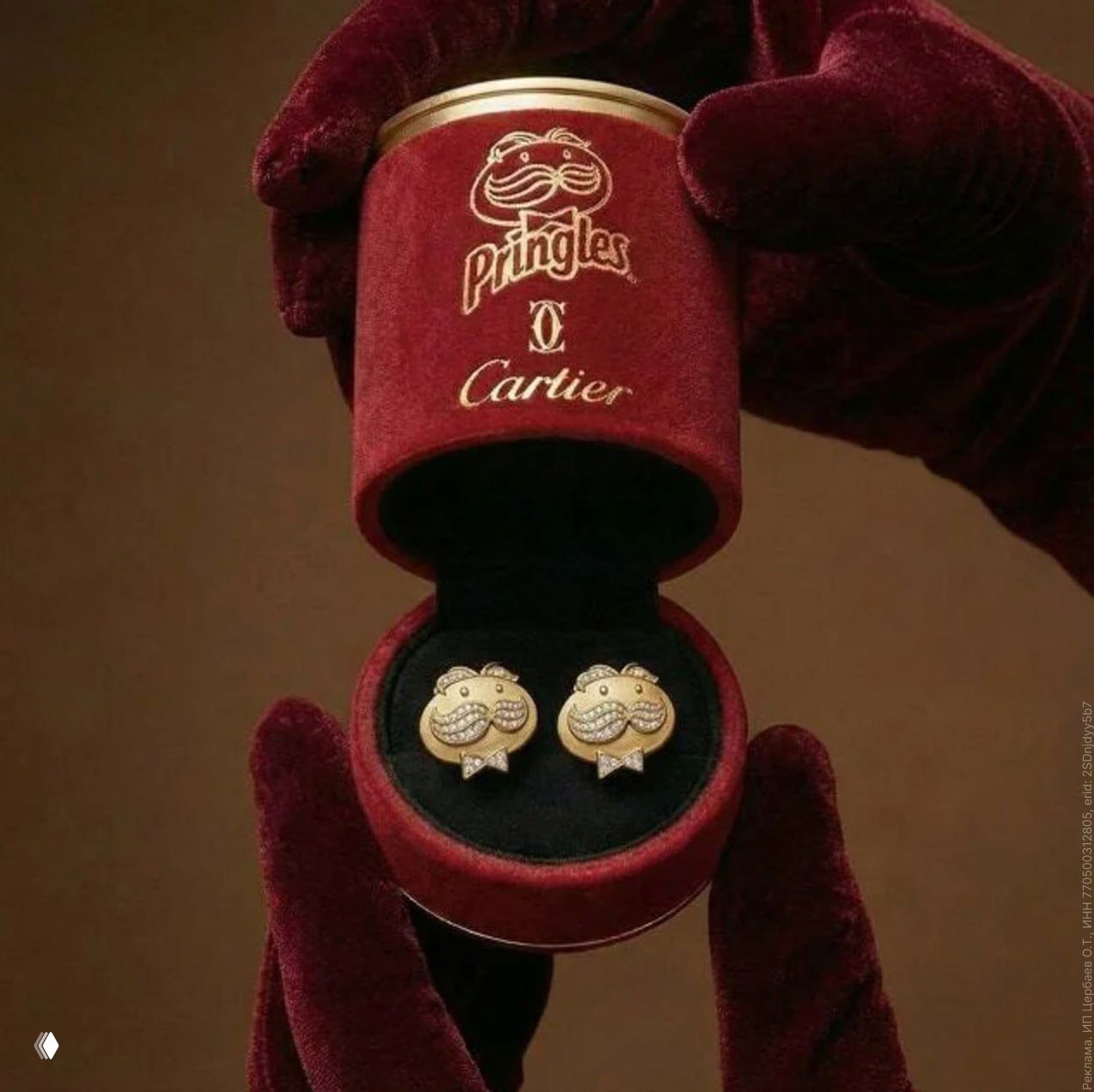 Красная бархатная шкатулка с логотипами Pringles и Cartier, в ней демонстрируются золотые запонки с усиками и маленькими стразами.