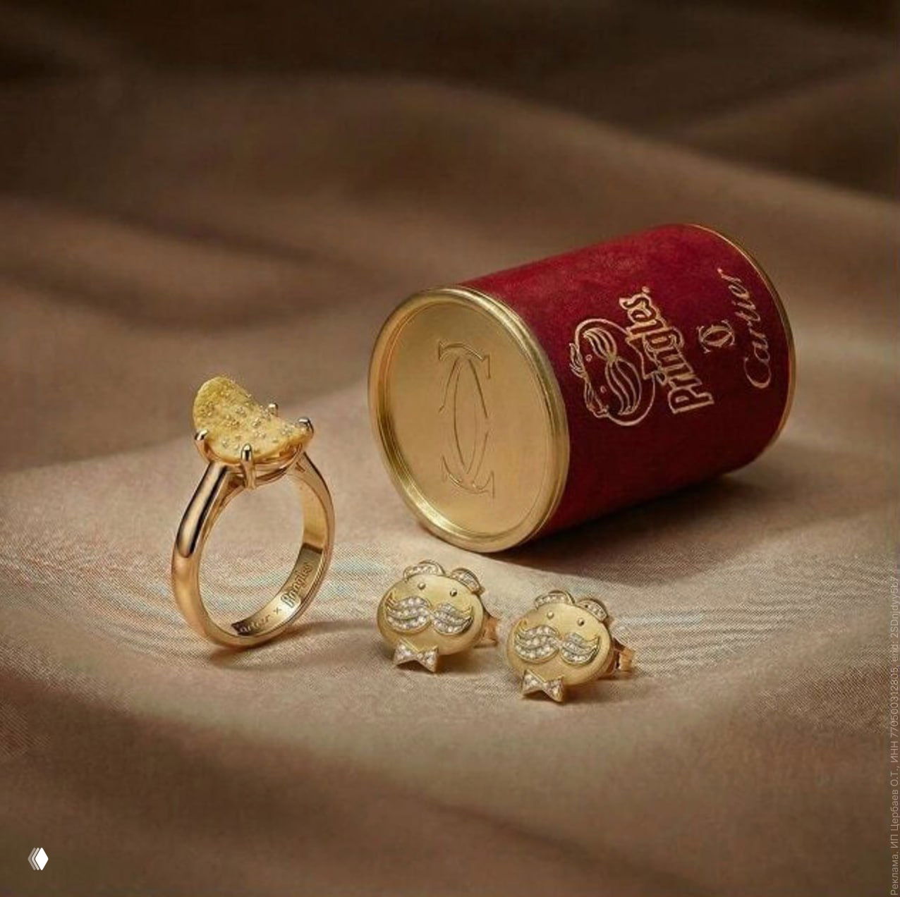 Натюрморт: золотое кольцо с чипсом, пара запонок и красная баночка Pringles x Cartier на тканевом фоне, студийная постановка.