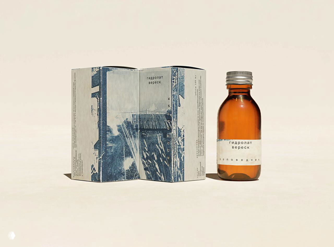 Книга или буклет рядом с флаконом гидролата, обёртка с синими отпечатками и маленькая бутылочка с жидкостью — часть фирменной системы.