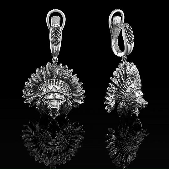 Пара серебряных подвесок с изображением стилизованных головных уборов и масок, детализированная фактура, чёрный отражающий фон, показано крупным планом.