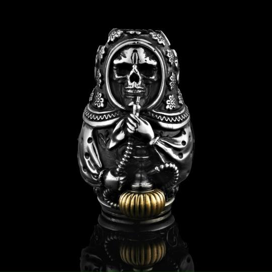 Матрешка-скелет — серебряная подвеска с чёрными патинами и золотым акцентом в основании, выразительная фактура, чёрный отражающий фон, показано крупным планом.