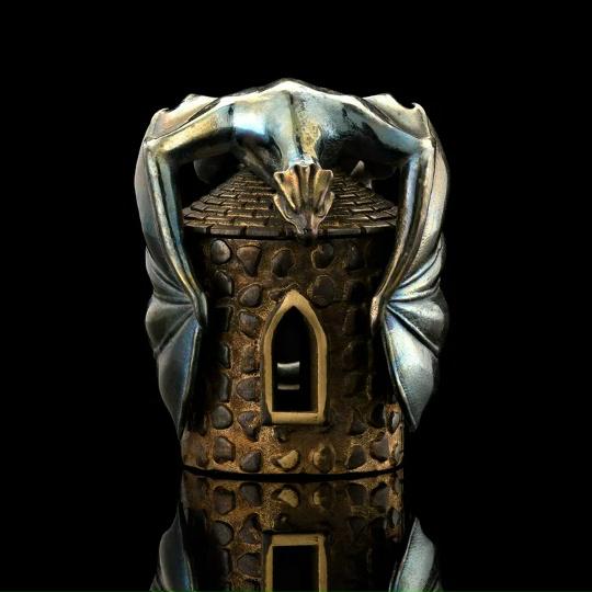 Детализированная бронзово-серебряная бусина в форме башни с окошками и орнаментом, тёмная патина и отражение на чёрном фоне, показано крупным планом.
