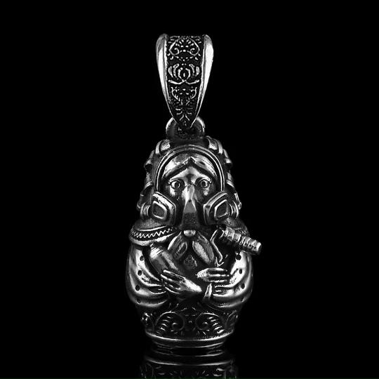 Подвеска в виде маленькой фигурки с трубкой и детальной гравировкой, серебро с глубокими тенями, чёрный отражающий фон, показано крупным планом.