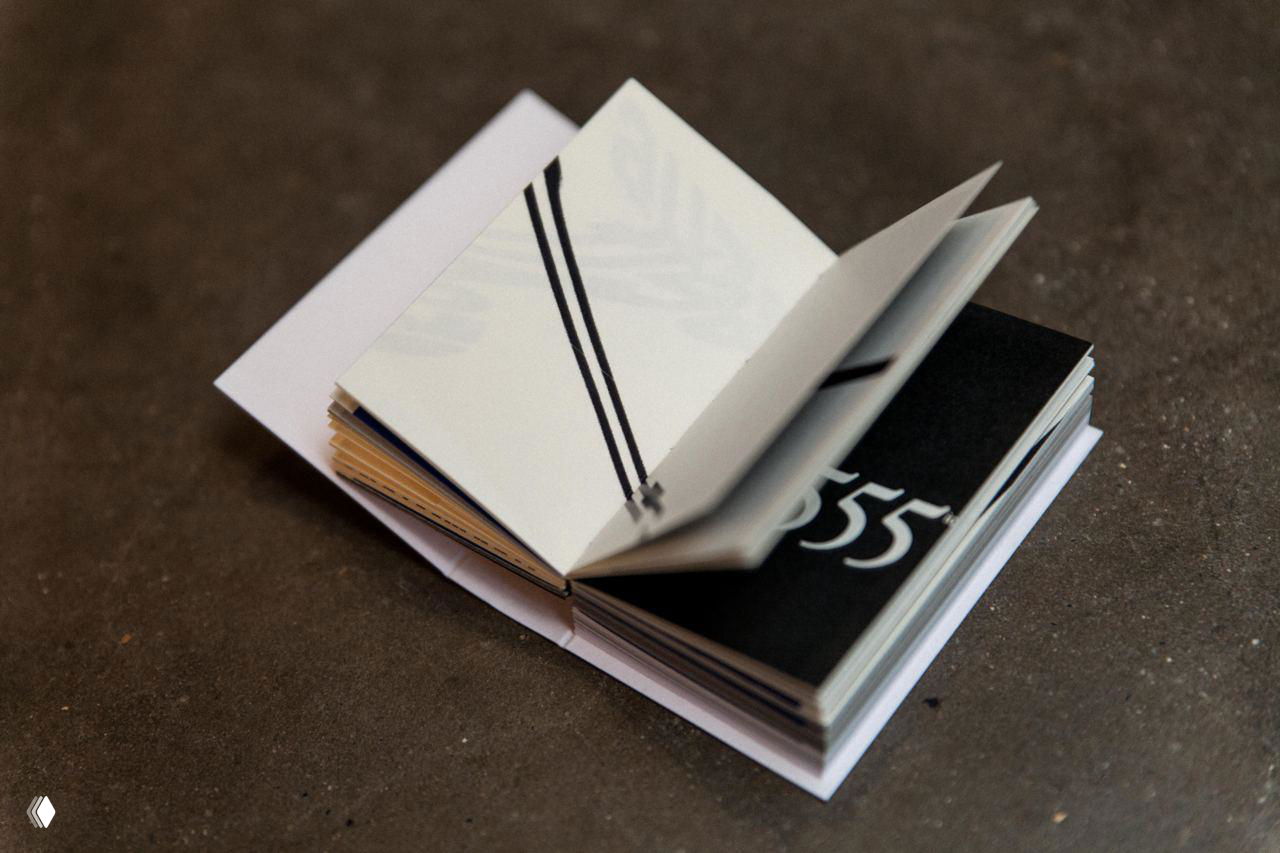 Человек читает маленькую книгу: в одном развороте видна чёрно‑белая фотография; кадр передаёт интимную сцену чтения и задумчивости.