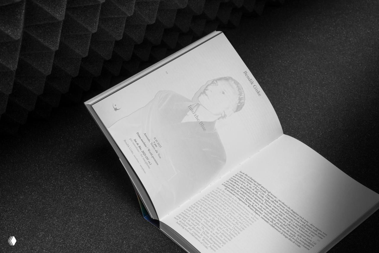 Фотография разворотов с текстовыми страницами и портретными врезками авторов, на фоне видны акустические панели для сценического настроя.