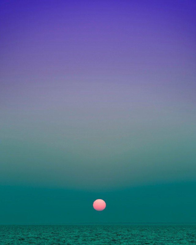 Панорамный кадр моря и неба: морская поверхность снизу и насыщенный зелёно‑бирюзовый градиент вверх; атмосферный снимок от Эрика Кахана.