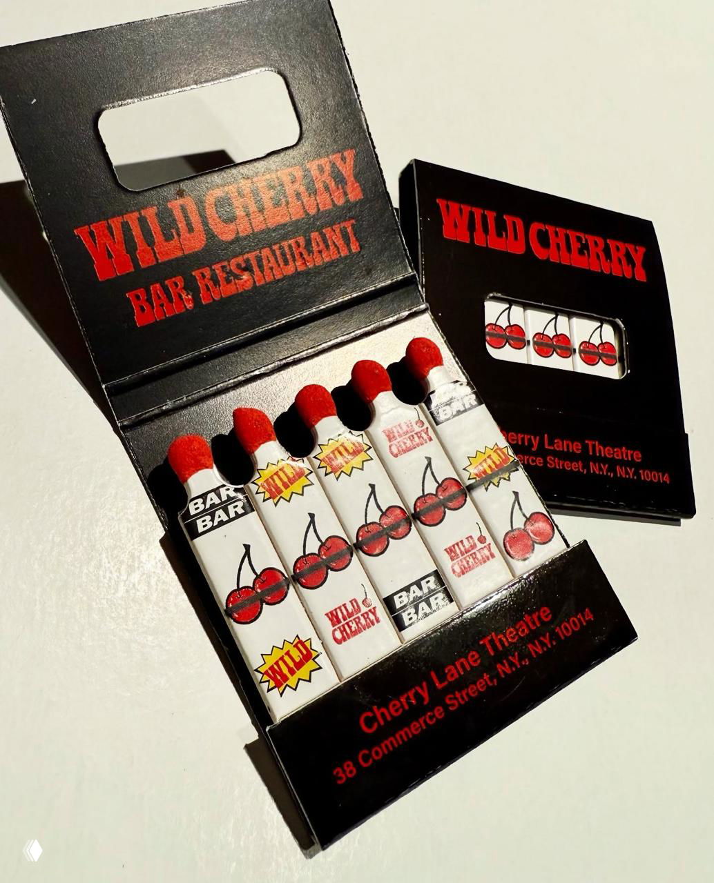 Чёрная коробка 'Wild Cherry' с яркими рисунками вишен: открытая упаковка, пять спичек с вишнёвыми значками и красными головками.