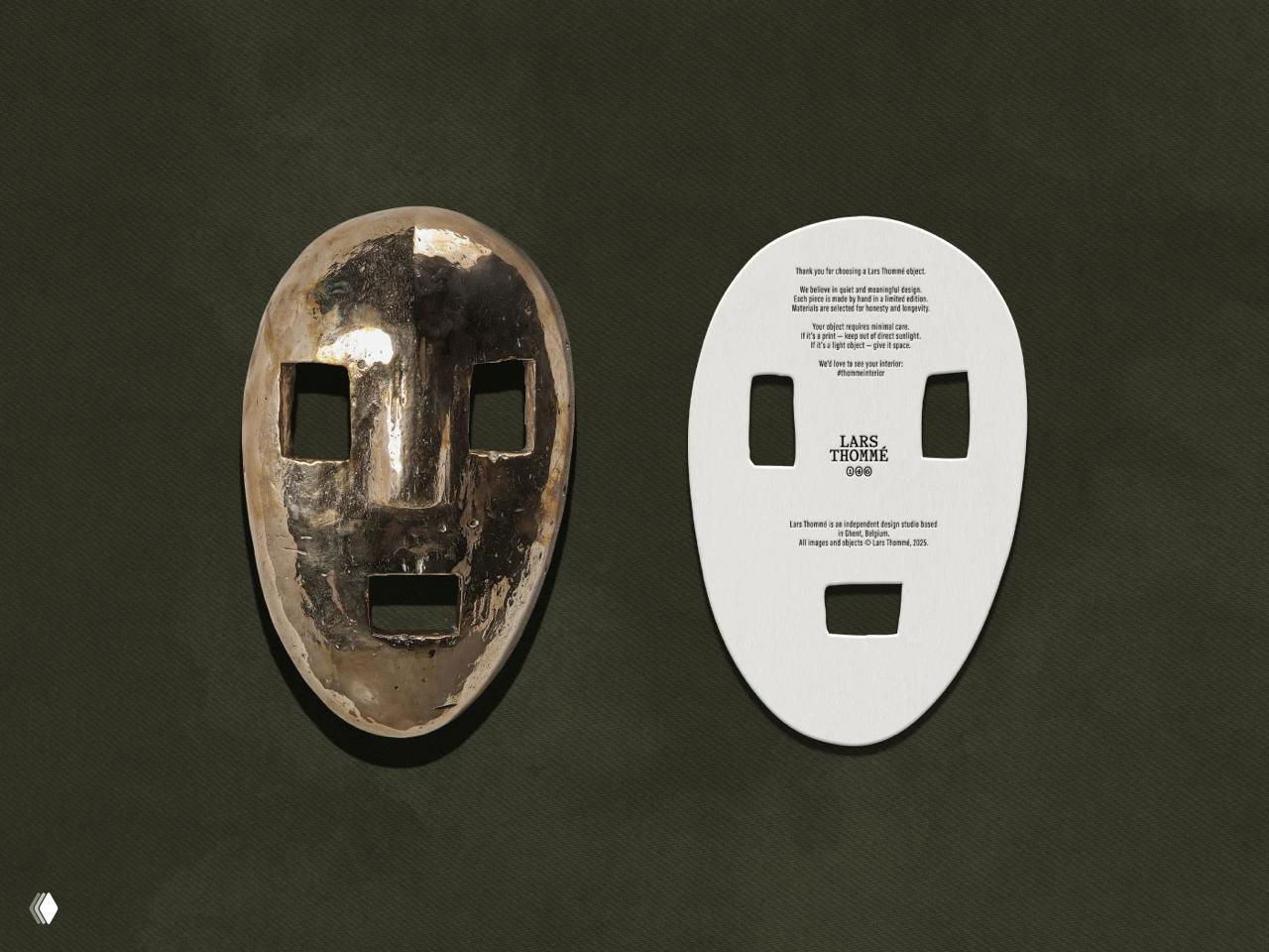 Слева старинная металлическая маска с патиной, справа вырубная белая бумажная вкладка с печатью логотипа LARS THOMÉ на тёмно-зелёном фоне.