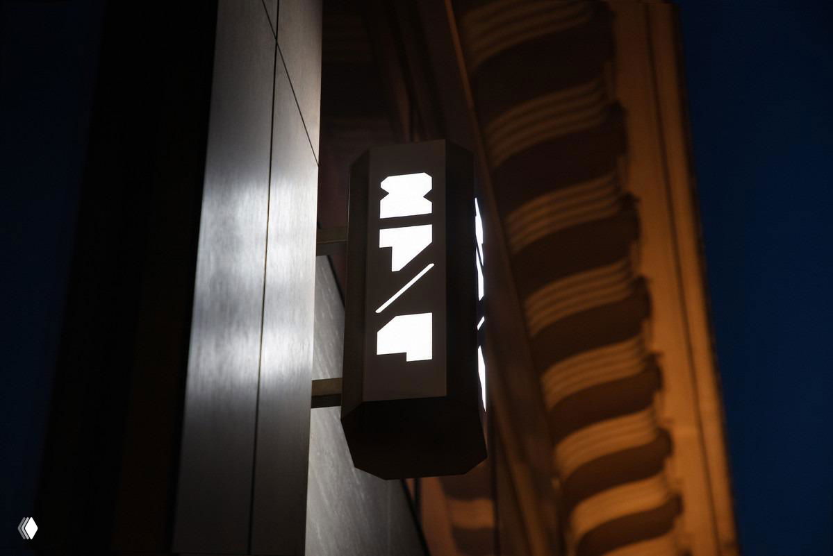 Светящаяся вывеска ресторана ночью: подсвеченный короб с графическим знаком и контрастной уличной подсветкой, часть фасадного решения бренда 27/4