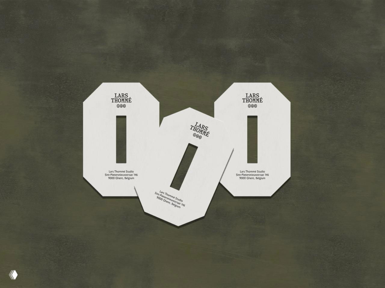Три белые картонные вкладки с вырезом и отпечатанным логотипом LARS THOMÉ, размещённые на текстурном тёмно-зелёном фоне в предметной композиции.