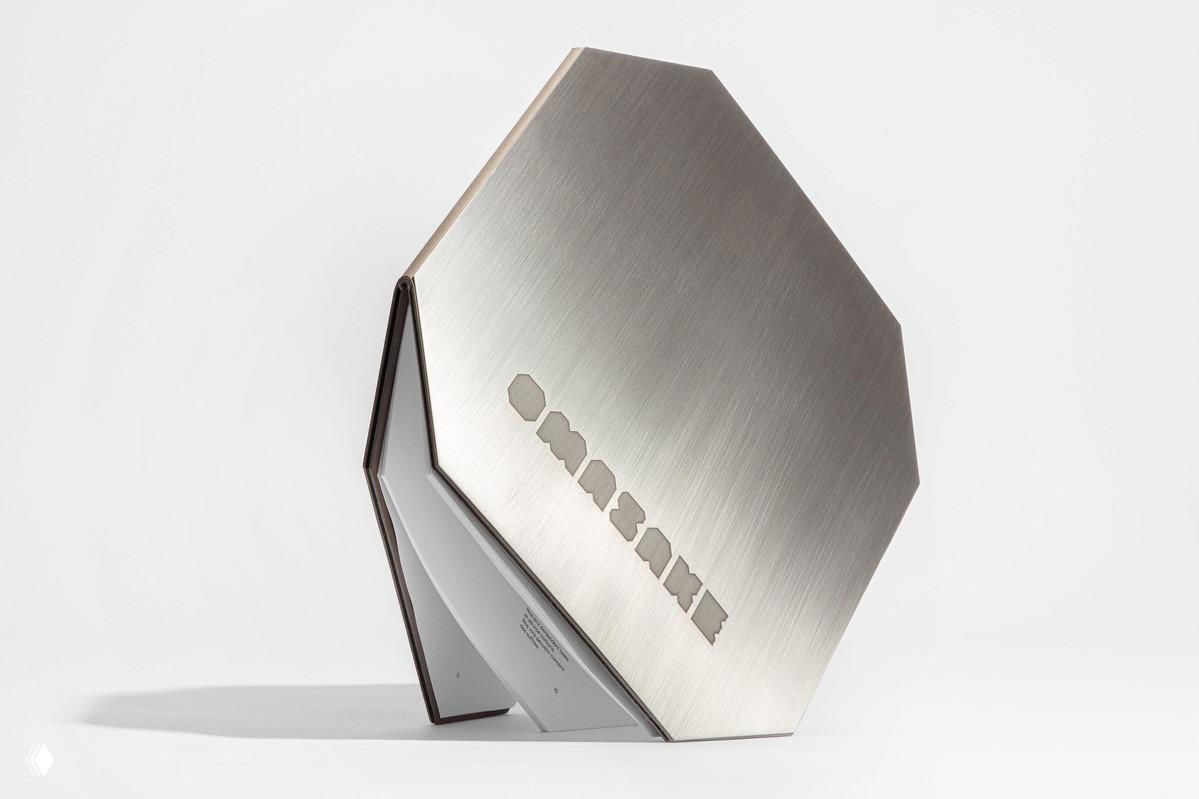 Полированный металлический восьмиугольный объект с вырезанным названием — дизайнерский элемент меню или подставки, демонстрация материальной отделки фирменного набора