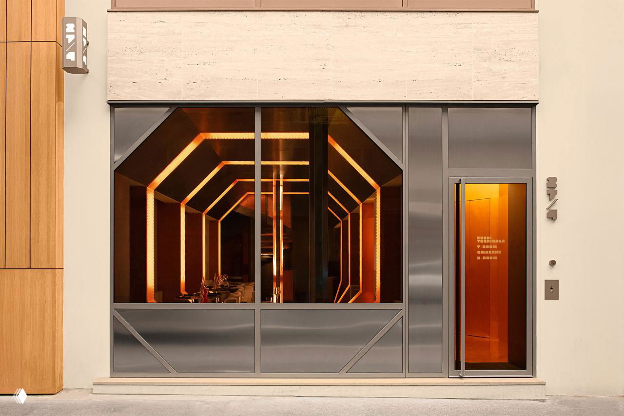 Фасад и вход ресторана: окно и дверная зона с видимыми внутри восьмиугольными арками и интерьерной подсветкой, сдержанный городской внешний вид заведения