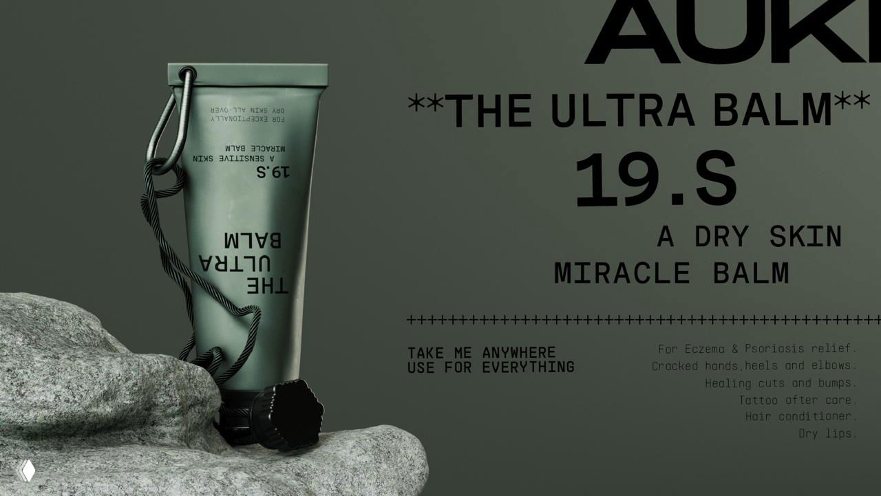 Крупный план зелёного тюбика AUKI, стоящего на камне; видно название продукта THE ULTRA BALM, шнур и детальную типографику упаковки.