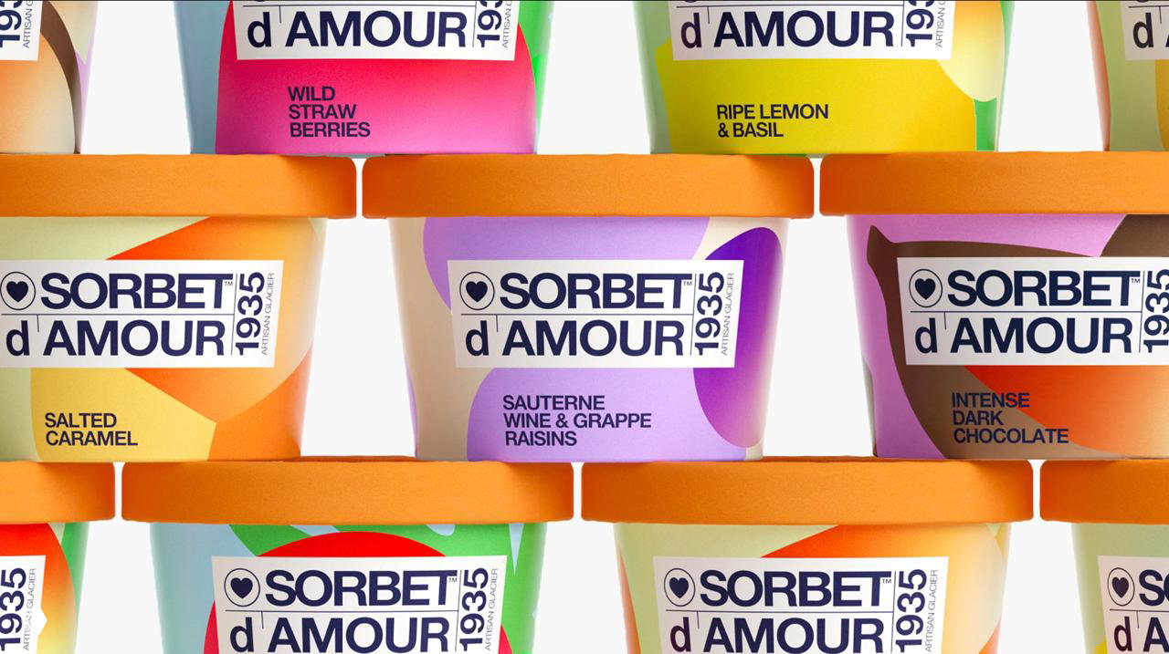 Стек из ярких стаканчиков Sorbet d'Amour, видны цветовые пятна, логотипы и оранжевые крышки — демонстрация серии вкусов и графических решений.
