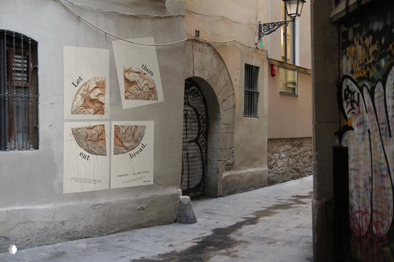 Постеры с изображениями хлеба на стене узкого переулка: пастельные тона, фрагментарная графика и спокойная монохромная палитра бренда.