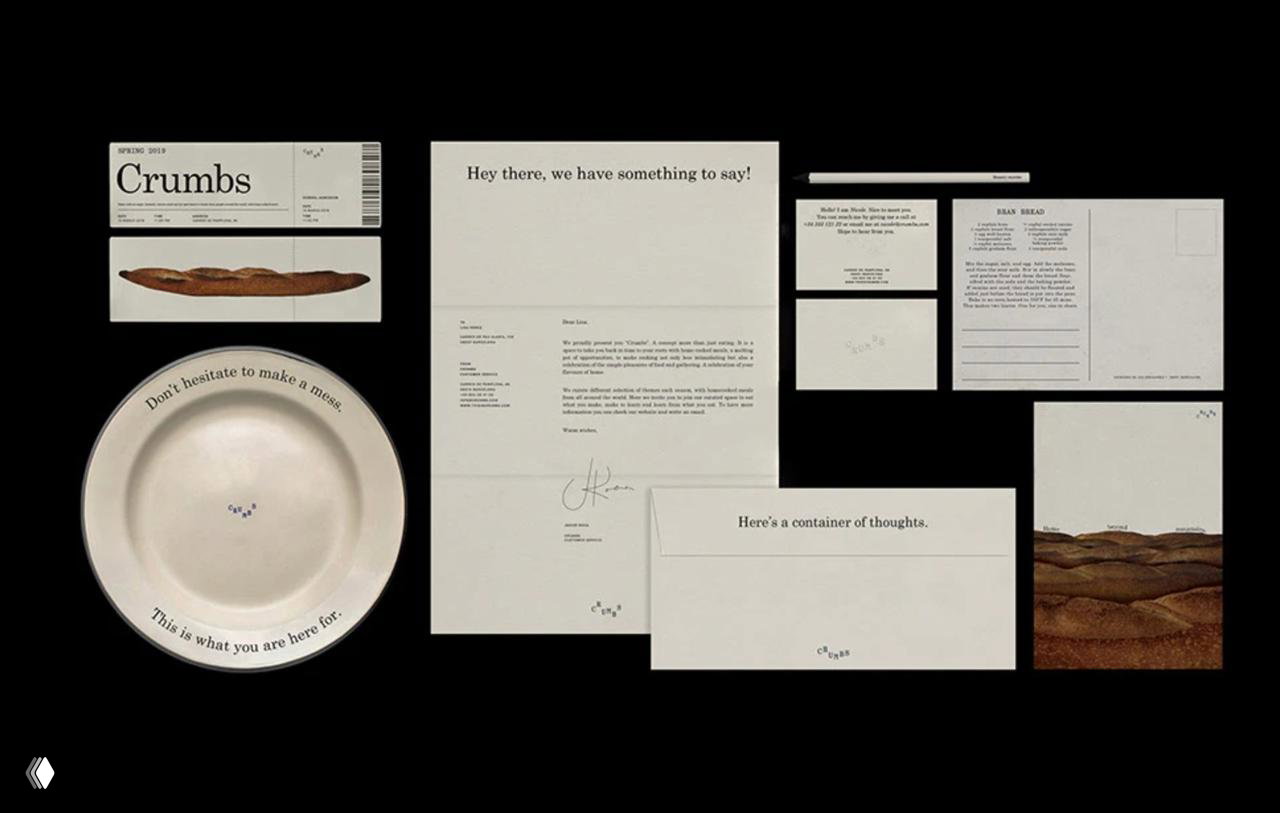 Набор печатных материалов Crumbs: тарелка с текстом, письма, открытки и конверты на чёрном фоне, демонстрирующие систему фирменных носителей.