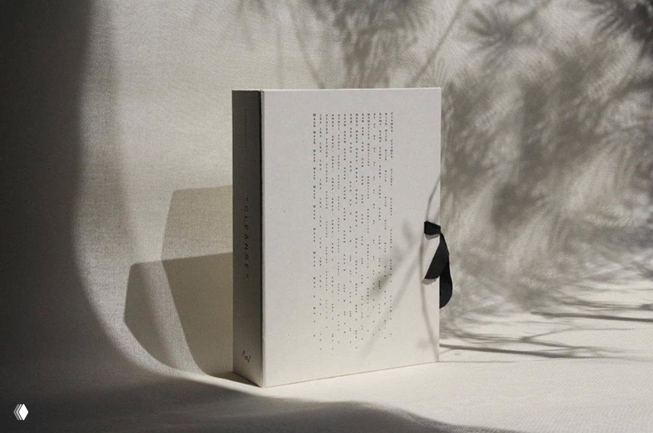 Изображение минималистичной упаковки или коробки с перфорацией и лентой на светлом фоне, тени растений усиливают ощущение премиальности бренда.