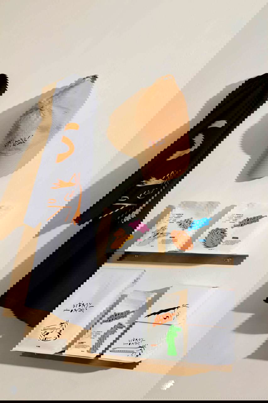 Фотография полки с мерчем и упаковками Story Horse: сумки, кепка и пачки кофе с яркими наклейками и линейными рисунками коня.