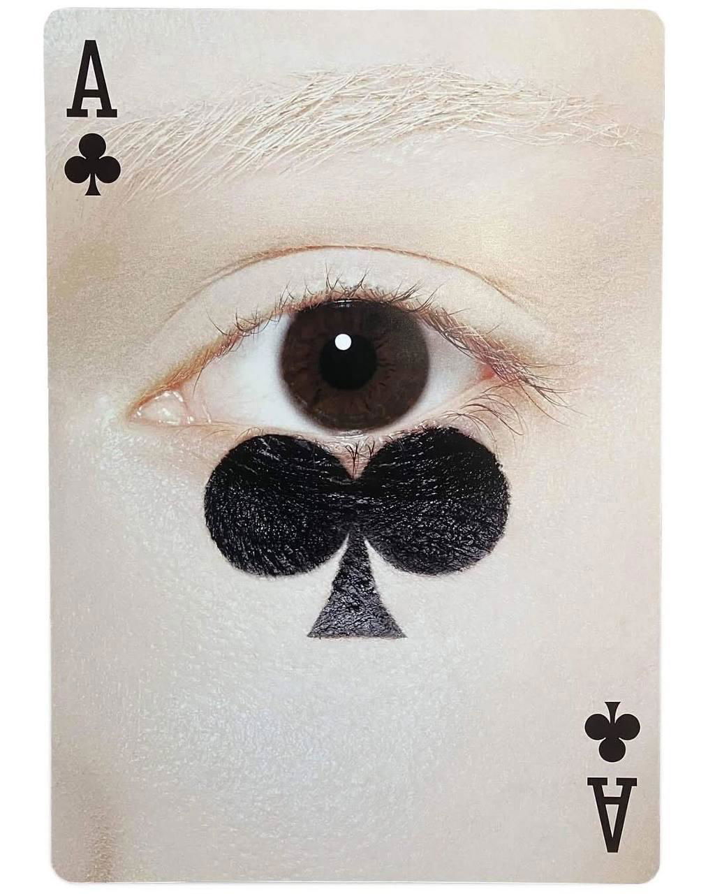 Карта с крупным глазом и контуром трефа, выполненным текстурой черных материалов под глазом — сюрреалистическая композиция портретного натюрморта.
