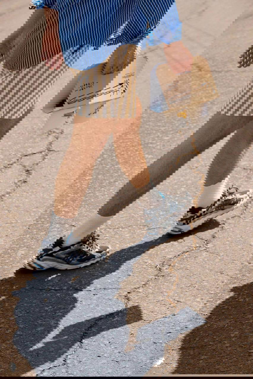 Кадр с человеком, несущим упаковку Story Horse на вынос: уличная сцена, крупный план ног и коробки с рисунком маскота.