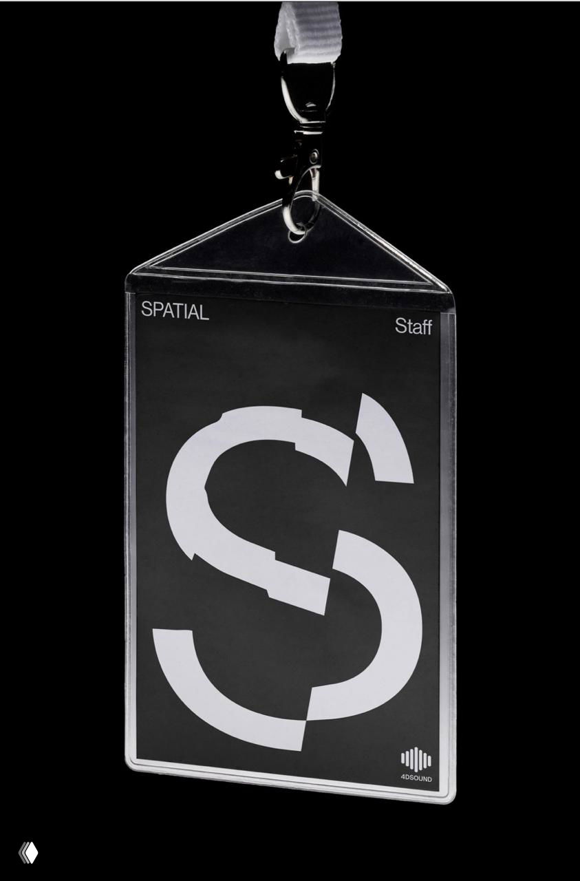 Прозрачный пропуск с крупной буквой S и минимальным набором элементов бренда Spatial, демонстрирующий перенос графики на физические носители и мерч.