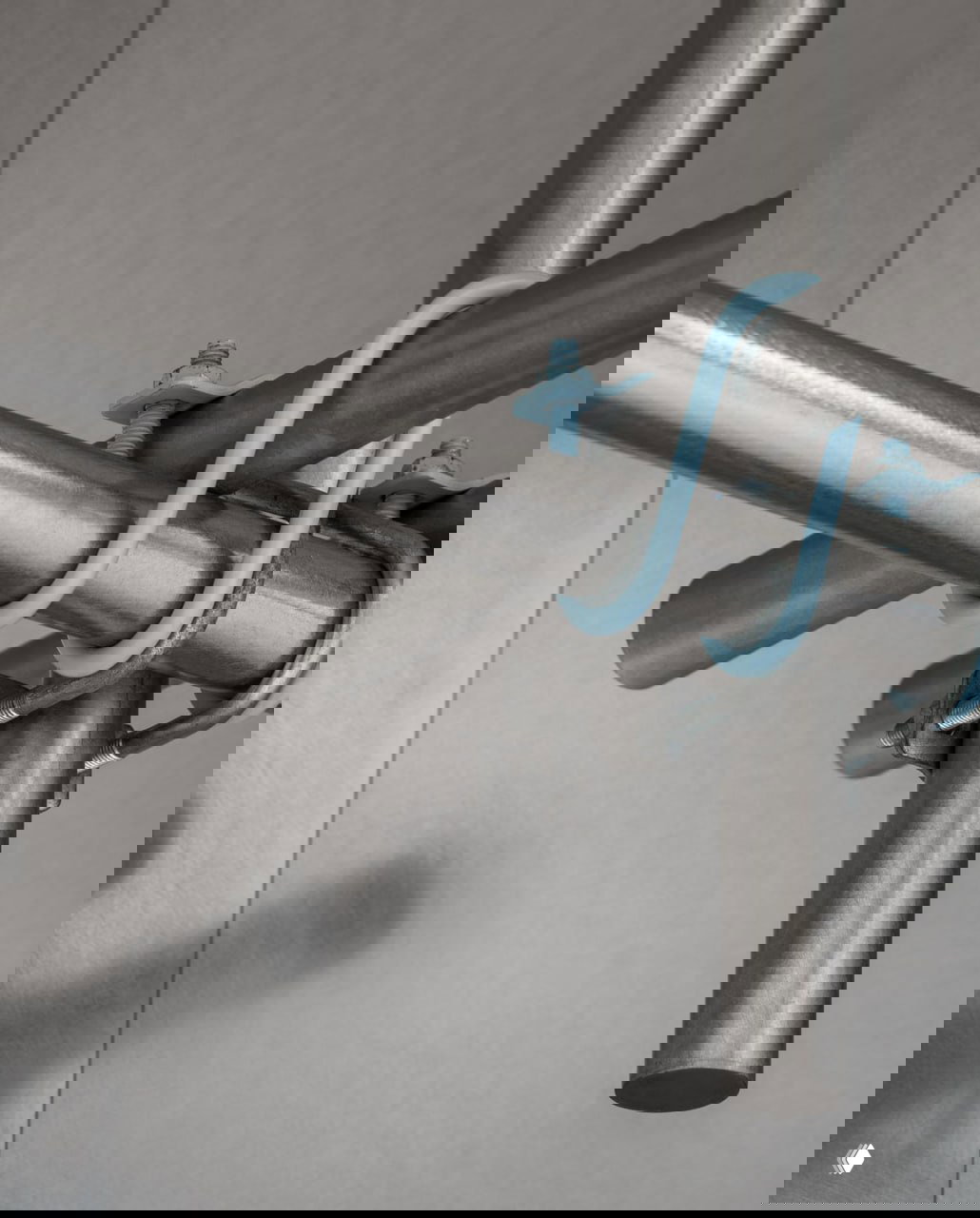 Съёмка монтажных металлических труб и скоб в интерьере, акцент на промышленные детали и простой механизм креплений в концептуальном дизайне кафе.