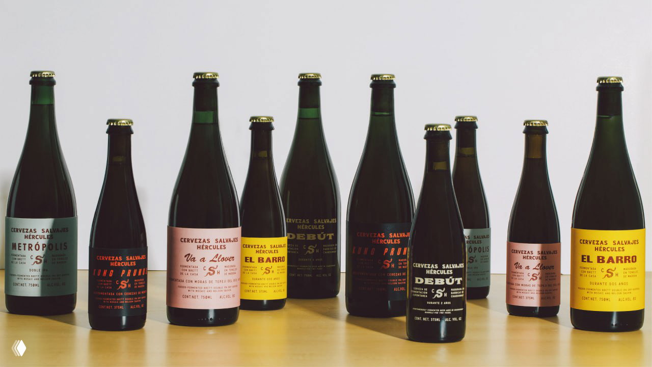 Широкий ряд бутылок Cervezas Salvajes Hеrcules разного формата и дизайна этикеток, выставленных на столе для демонстрации линейки.