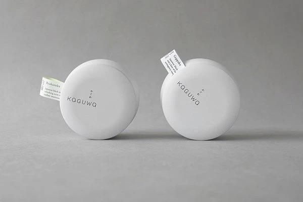 Две круглые банки Kaguwa, вид сверху и сбоку; логотип нанесён тонкой, изящной гарнитурой, форма крышки подчёркивает рустикальную простоту