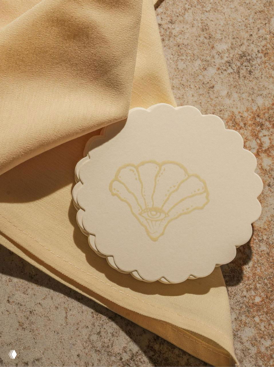 Круглые бумажные подставки‑костеры с тиснёной раковиной и глазом, кремовая бумага на фактурной поверхности в контексте фирменного стиля Selene.