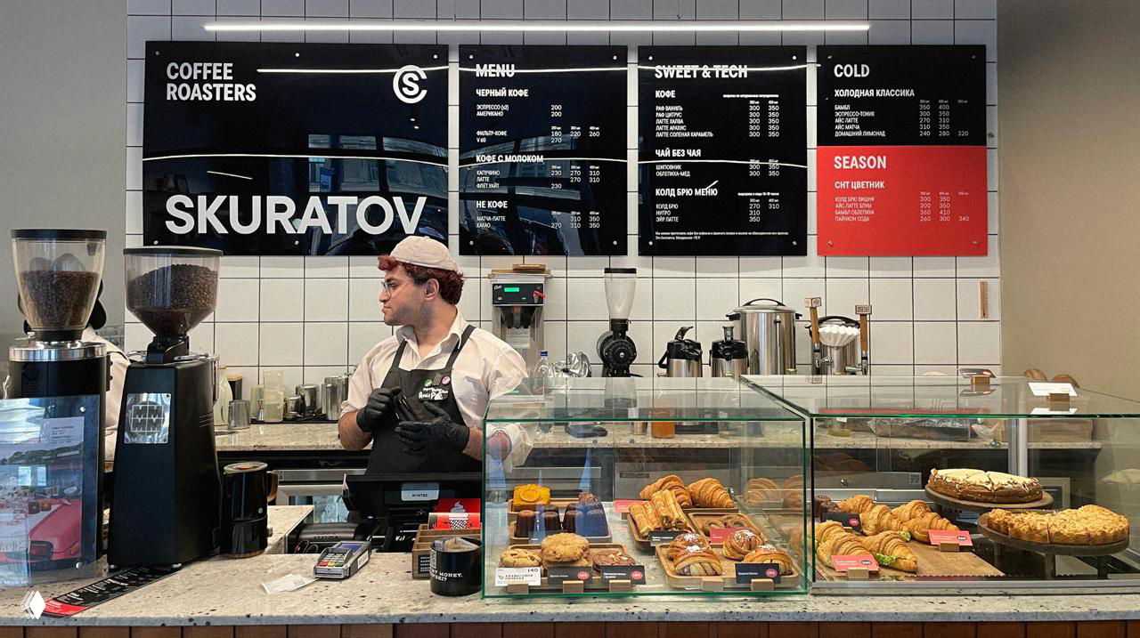 Куча однотонных бумажных стаканчиков с крупной надписью SKURATOV и логотипом, чёрно‑белая монохромная серия упаковки для напитков.