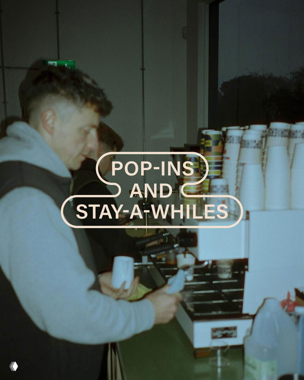 Фотография человека у кофемашины, на заднем плане стопки бумажных стаканов с брендингом Cornershop и типографской надписью.