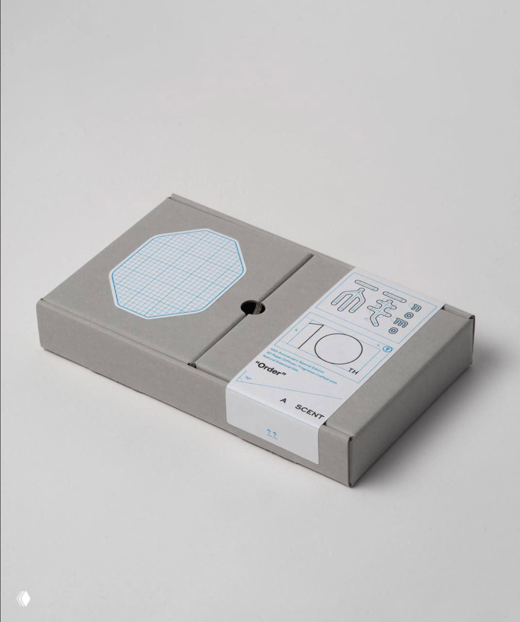 Серый прямоугольный бокс набора «Order» с печатью миллиметровой сетки и схематичными деталями — спокойная студийная фотография упаковки спереди.