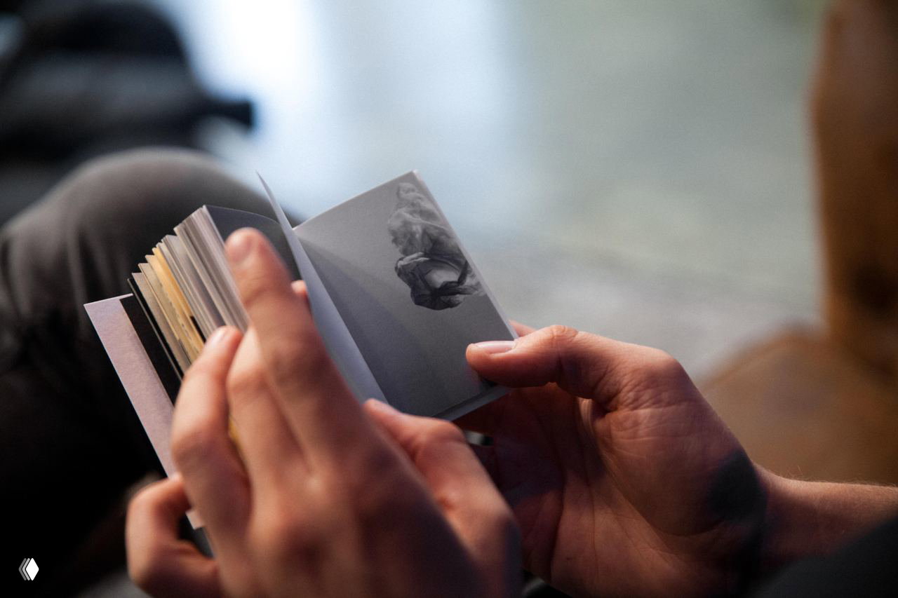 Человек кладёт компактную книгу в карман джинс, иллюстрируя карманный формат и портативность издания относительно человеческой руки и одежды.