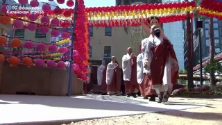 Гуманоидные роботы в монашеских одеяниях идут по дорожке во время церемонии посвящения в буддийском храме в Южной Корее; видны украшения и здания.