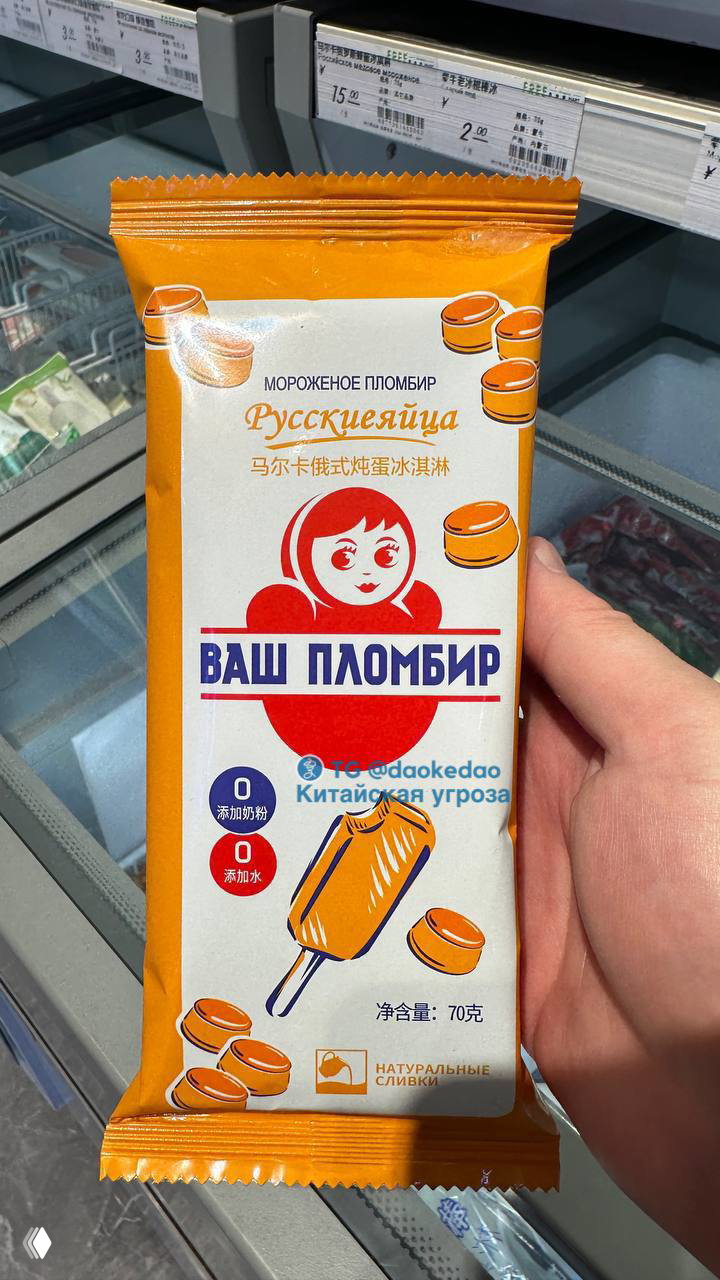 Фотография китайского мороженого в упаковке с кириллическим брендом «Ваш пломбир», изображением матрёшки, на витрине магазина.