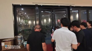 Группа людей у раздвижных стеклянных дверей в помещении ночью — кадр из видео, снятого во время тайфуна провинции Хубэй.