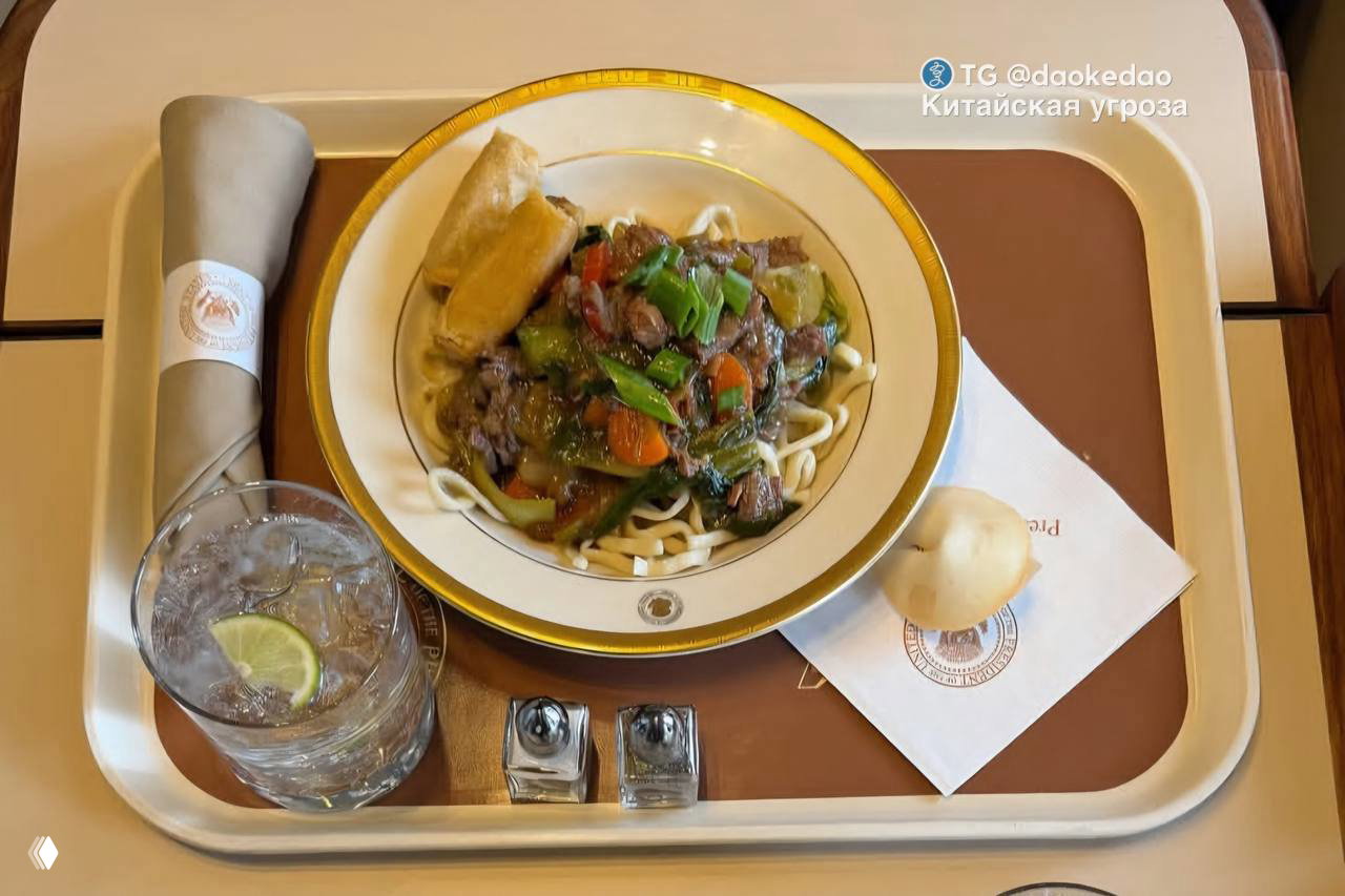 Тарелка с говяжьей жаркой (beef stir fry) на лапше, рядом весенний ролл, булочка и напиток на подносе сервировки Air Force One.