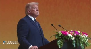 Дональд Трамп стоит за трибуной на официальном мероприятии в Китае; в костюме, видно декор и букет цветов на подиуме.