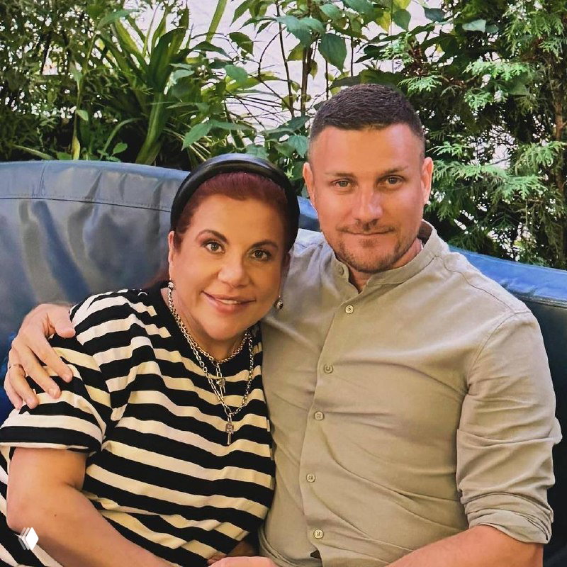 Портрет Марины Федункив вместе с мужем Стефано Маджи на диване на фоне зелёных растений: пара сидит и улыбается после интервью о беременности и ЭКО